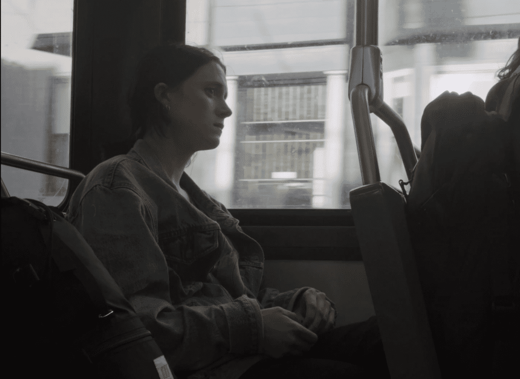 A still from a movie with Nancy sitting on a bus.